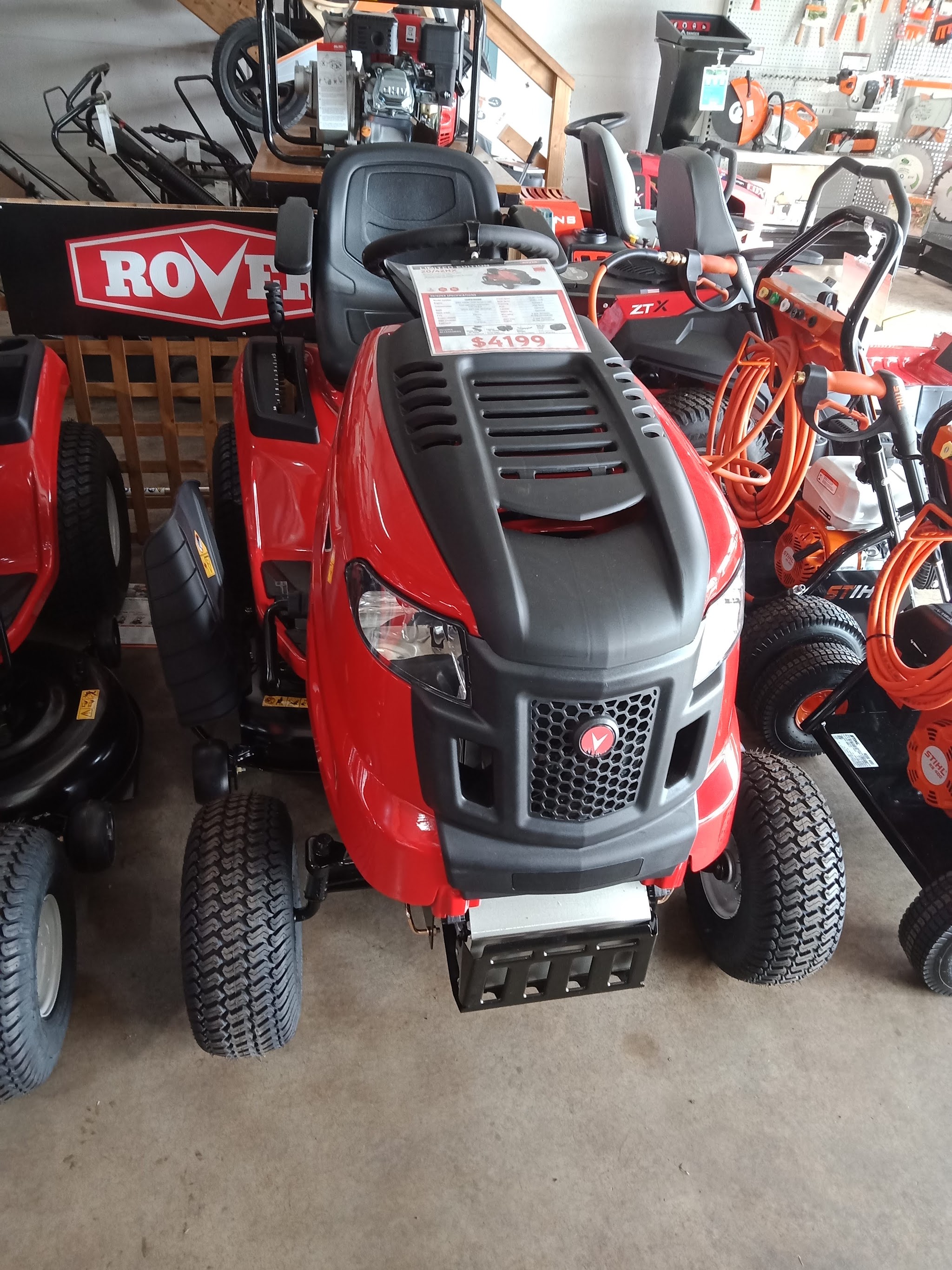 A red Rover ride on mower in the Camperdown Mowers showroom, alongside a Gravely zero turn and Stihl pressure washers